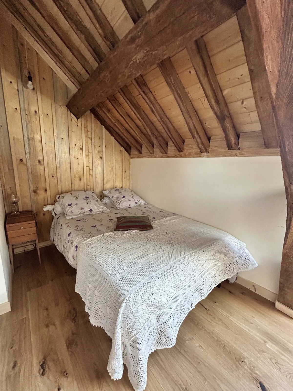 Wood-panelled attic bedroom with white bedding