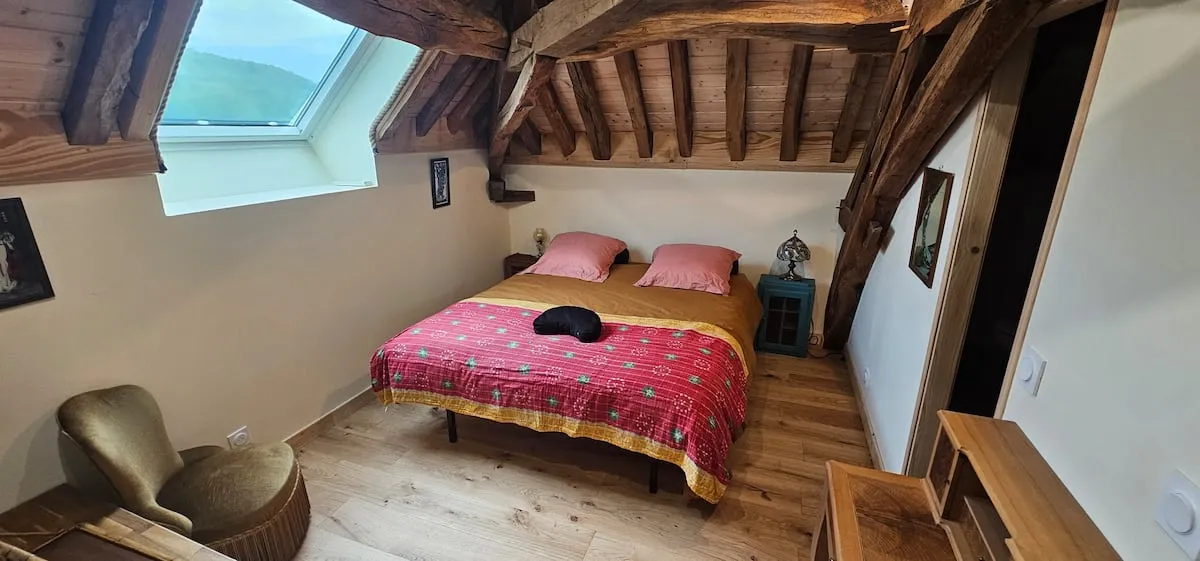 Attic bedroom with pink bedspread and skylight