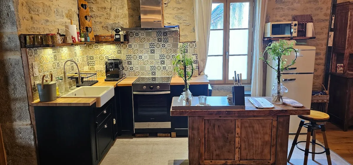 Fitted kitchen with dark cabinets and stone wall